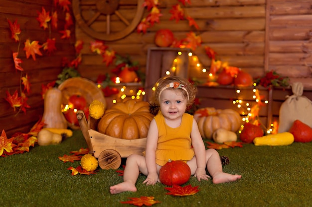 Babymeisje in herfst decor met pompoenen, bessen en bladeren voor thanksgiving of halloween