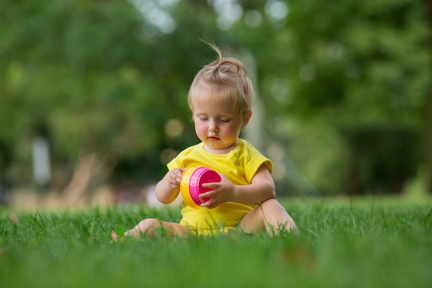 Babymeisje in het gele bodysuit spelen op groen gazon