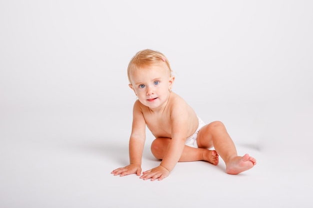 Babymeisje in luier zittend op witte achtergrond