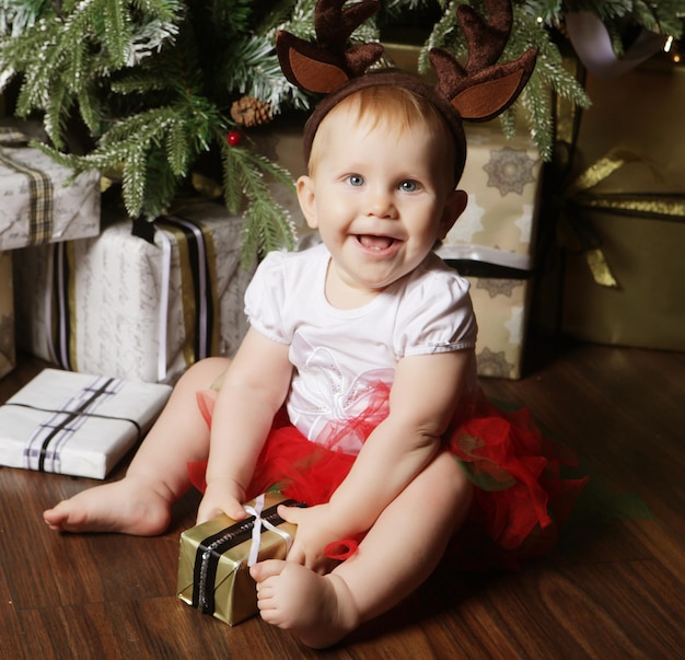 Babymeisje met de geschenkdoos in de buurt van kerstboom versieren Happy time