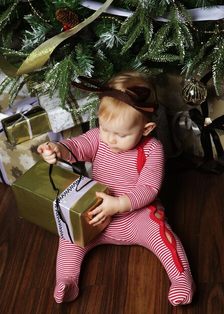 Babymeisje met de geschenkdoos in de buurt van kerstboom versieren Happy time