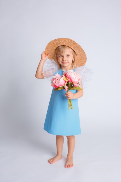 Babymeisje met een boeket bloemen en een strohoed