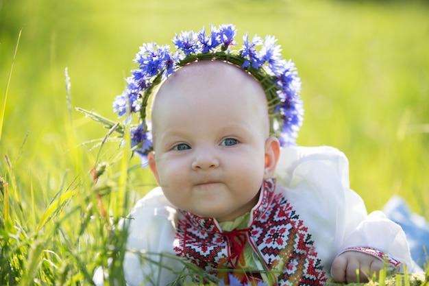 Babymeisje met geborduurde korenbloemen. Symbool van Wit-Rusland