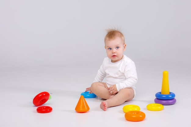 Babymeisje spelen kleurrijke regenboog speelgoed piramide zittend op de vloer