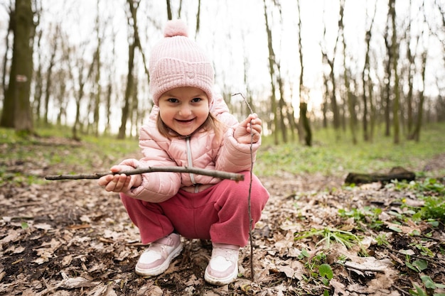 Babymeisje spelen met stokken in de lente bos