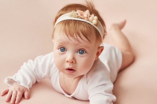 Babymeisje van vier maanden ligt op een lichtroze muur