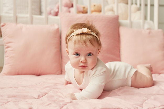 Babymeisje van vier maanden ligt op een roze muur