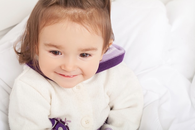 Babymeisje verstopt zich onder de witte deken