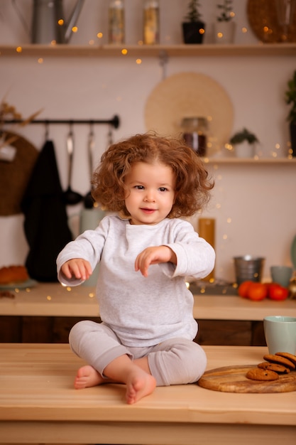 Babymeisje zit in de keuken van kerstmis op tafel