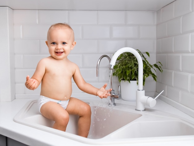 Babymeisje zittend op een gootsteen in de keuken