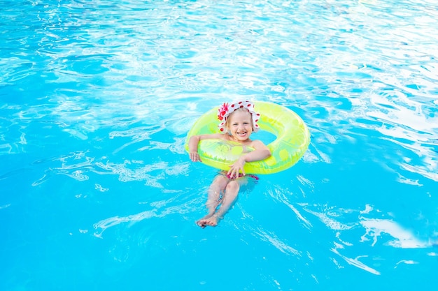 Babymeisje zwemt in het zwembad met een opblaasbare gele cirkel in de zomer het concept van reizen en recreatie en glimlacht in panama