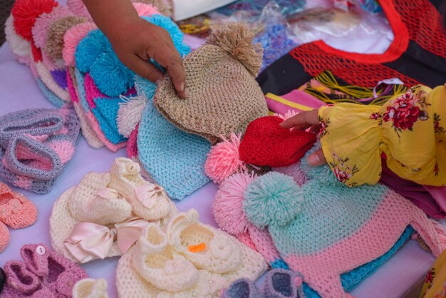 Babymutsjes en pantoffels gebreid met kamgaren Kleurrijke breisels op een straatmarkt