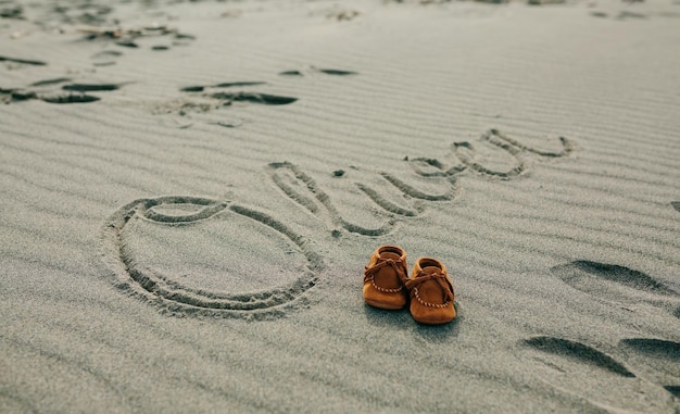 Babynaam geschreven in zand met schoenen