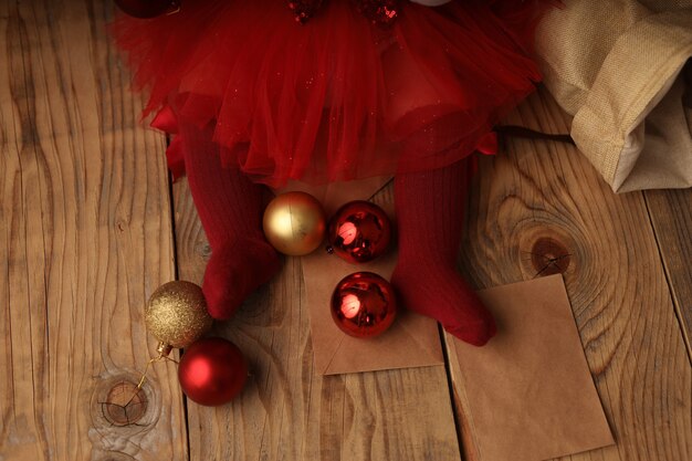 babys feet in red socks around Christmas balls