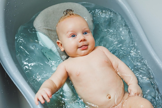 Foto i primi bagni dei bambini prendersi cura di un neonato fare il bagno di un bambino in una vasca da bagno