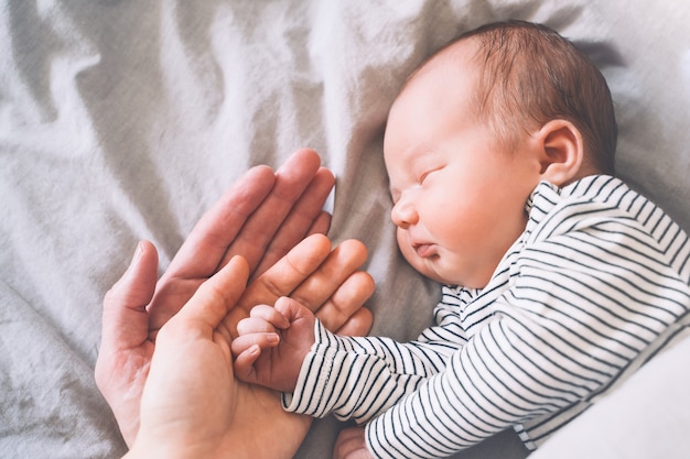 Babys hand into parents hands family happiness concept sleeping newborn in first days of life