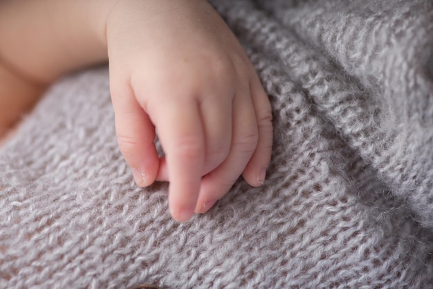 Photo a babys hand is on a gray blanket with a white background