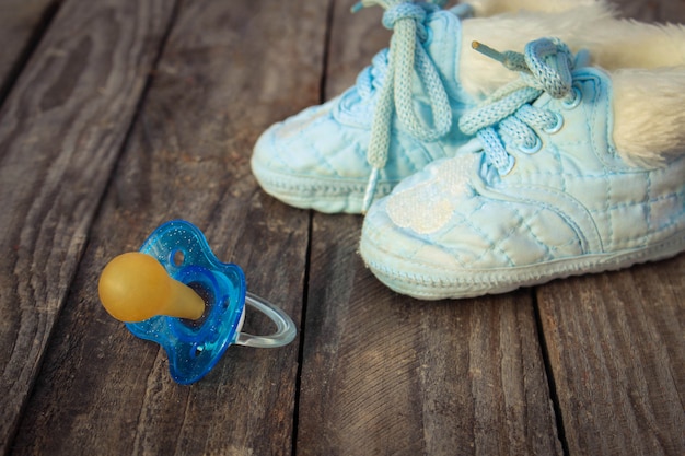 Babyschoenen en een fopspeen op de oude houten oppervlak