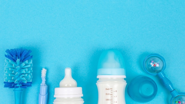 Babyvoeding achtergrond met flessen met melk en flessenborstel accessoires op blauwe tafelblad weergave frame kopie ruimte