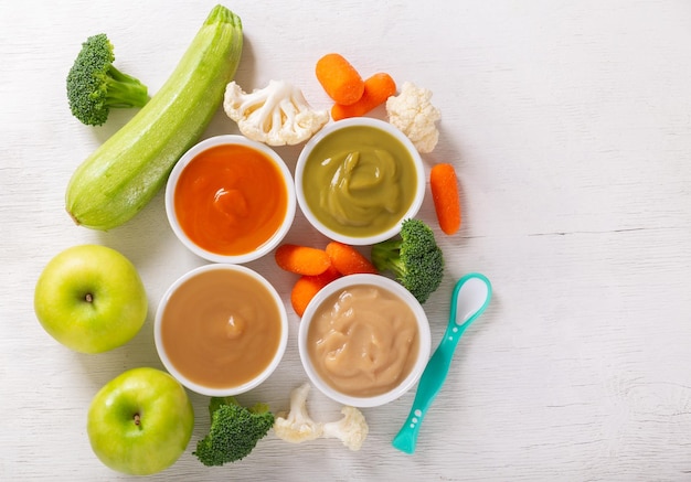 Babyvoeding Diverse soorten kommen groente- en fruitpuree met ingrediënten voor het koken van bovenaanzicht