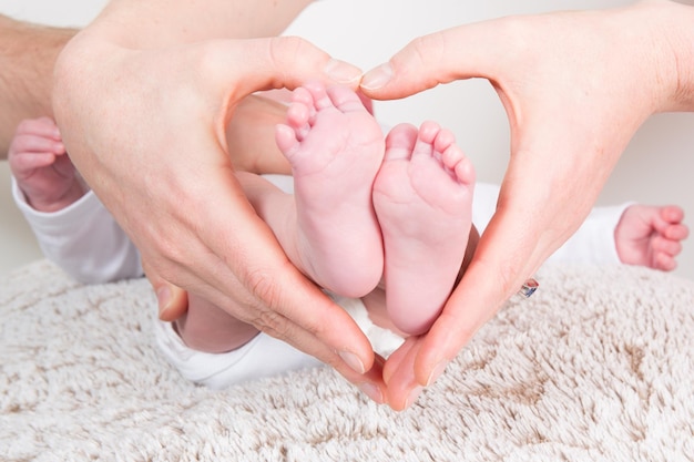 Babyvoeten in moederhanden in de vorm van een haard