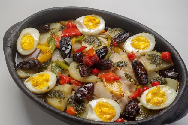 Bacalhau, 후추, 감자, 양파, 블랙 올리브, 올리브 오일을 뿌린 삶은 계란과 함께 제공