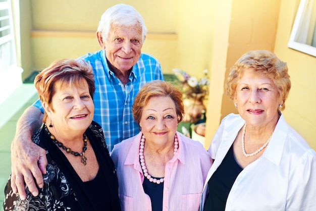 Back to being ourselves Shot of a group cheerful elderly people smiling and posing for the camera outside of a building