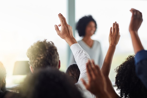 Foto indietro uomini d'affari e mani alzate per le domande al seminario della conferenza o alla riunione pubblico di gruppo e mano alzata per domanda o risposta voto della folla e formazione alla presentazione del workshop