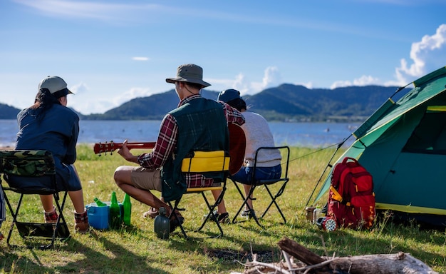 Back camping camp in nature happy friends group playing guitar in summer at nature forest