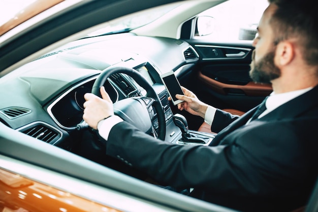 Back cropped photo of young businessman using smart phone in car