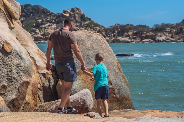 Back Dad care Son near sea walk spend time together explore new Concept father day family union fatherhood raising boy influence in happy child live worldview Man hold kid hand show with finger