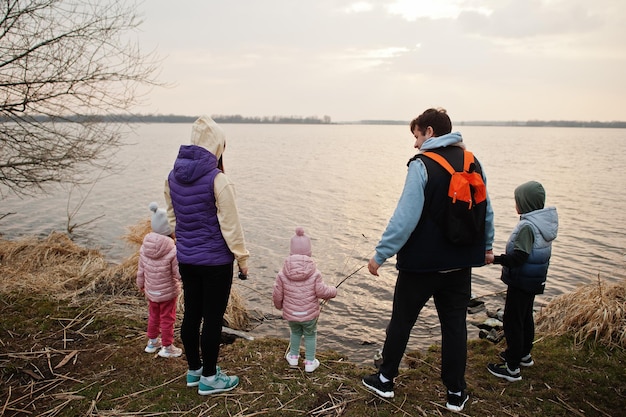 湖のほとりに 3 人の子供を持つ家族の後ろ姿