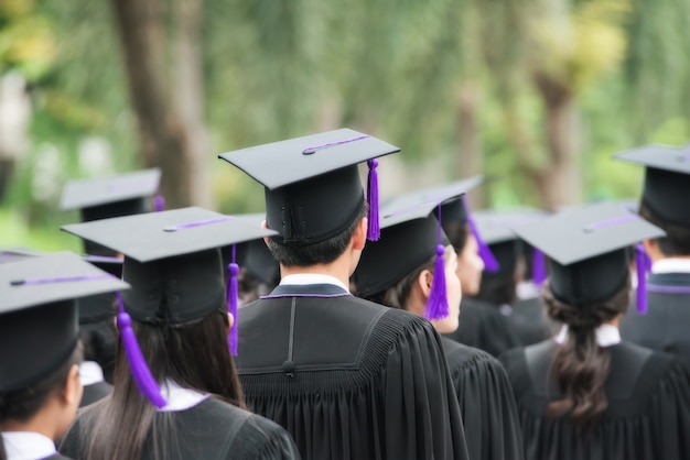 Back of graduates during commencement at university. Graduate walking.