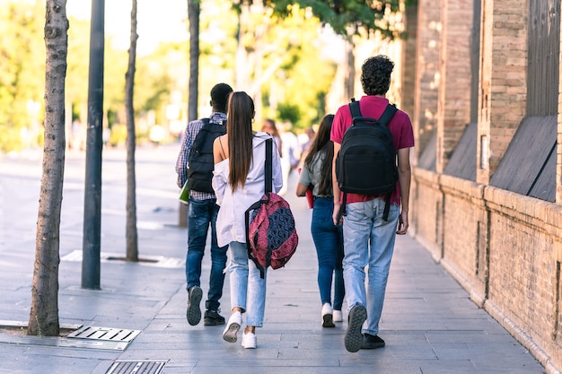 Foto indietro di un gruppo di amici di diverse etnie che camminano per strada