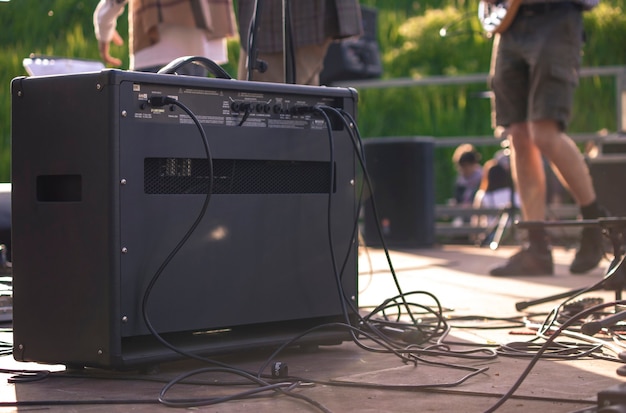 Back of a guitar amp on the stage of the concert with musicians playing on the background