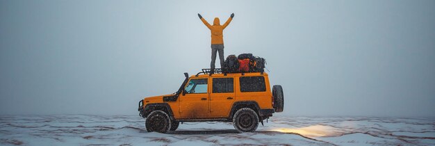 冬の遠征で自然の中でSUVの屋根の上に立っている幸せな男の旅行者の背中