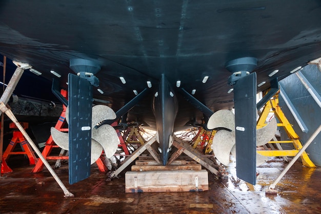 Back of a large motor yacht in a dry dock Two propellers and zinc protective inserts