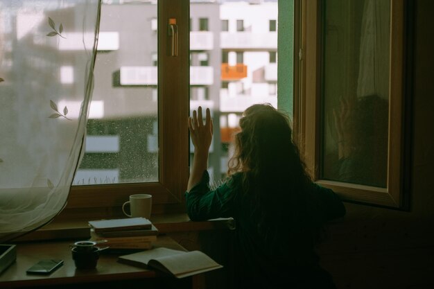 the back of a lonely girl who waves her hand out the window and says goodbye and misses