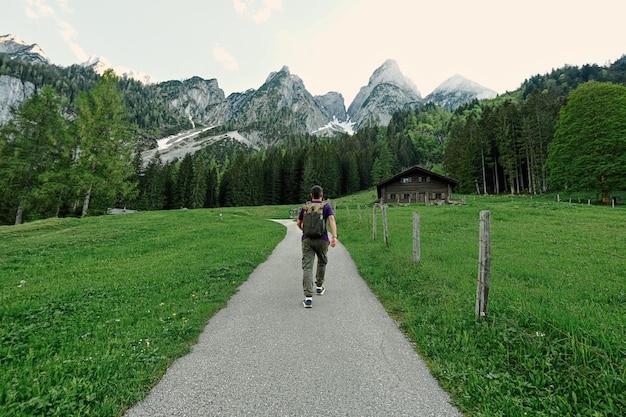 Back of man with backpack walking in mountains at Vorderer Gosausee Gosau Upper Austria