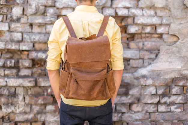 Back of man with brown leather backpack