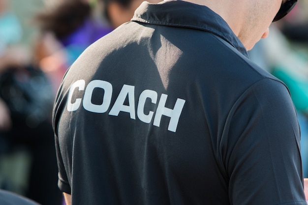 사진 coach라는 단어가있는 coach의 검은 색 셔츠 뒷면