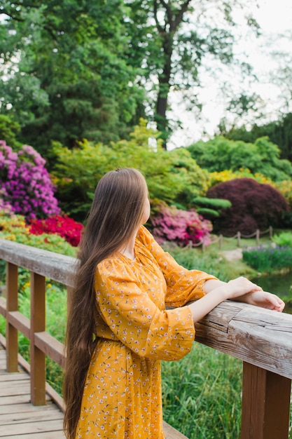 写真 休暇旅行中に屋根の赤いタイルの家でヨーロッパの街を楽しんで、明るい晴れた日に遠くを見ている帽子とバックパックを身に着けている女の子の旅行者の背中