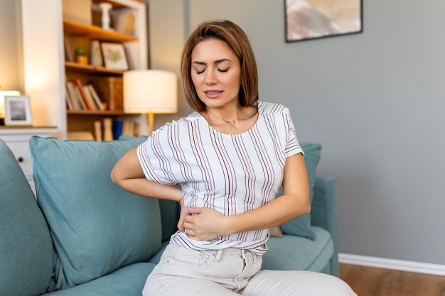 Back Pain Closeup Of young woman Having Spinal Or Kidney Pain Backache Girl Suffering From Painful Feeling Muscle Or Nerve Pain Holding Hands On Body Health Issue Concept