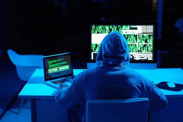 back person or hacker with laptop in dark for cybercrime malware or phishing for stealing online data programmer night or software update on computer with hacking expert writing algorithm system