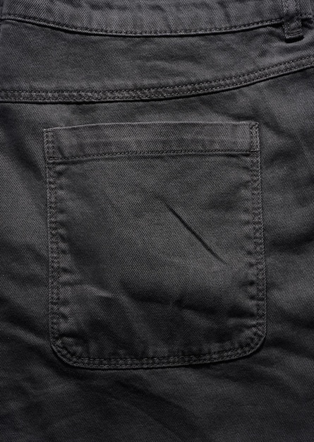 Back pocket of black jeans close up