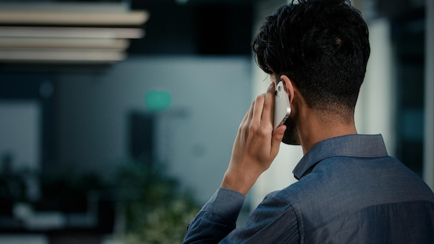 Back rear view man talking phone indoors unknown adult indian businessman employer office worker