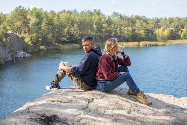 素敵な素敵な配偶者のバックリアビュー太陽が輝く石の上に座っている青い湖で自由な時間を過ごす