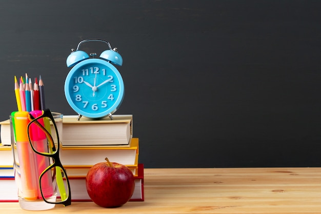 Torna a scuola mela e libri con matite e occhiali sulla lavagna.