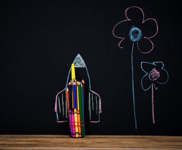 Back to school black background the missile made with pencils, drawing crayons books