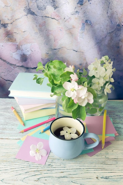 Back to school bouquet of apple tree flowers stack of books cup\
of tea and stationery